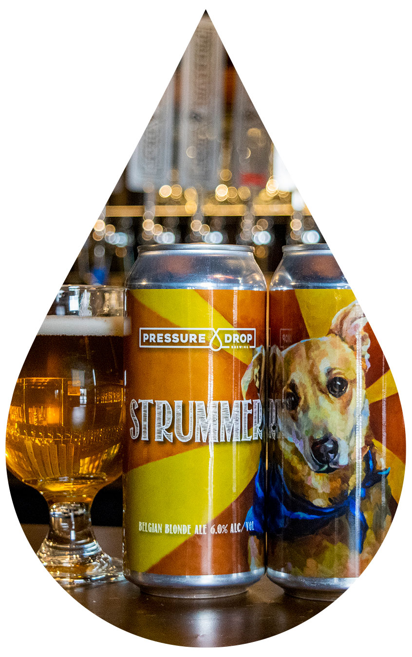 Two cans of Strummer next to glass filled with beer